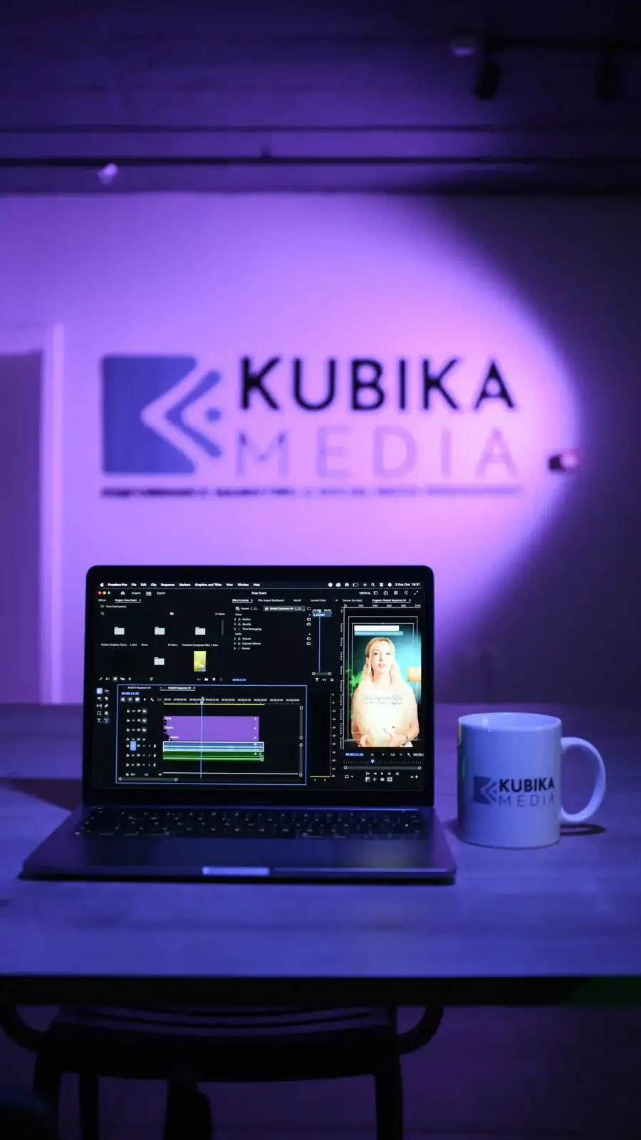Kubika Media ofisinde mor ışıklı logo duvarı önünde kurgu yapılan dizüstü bilgisayar