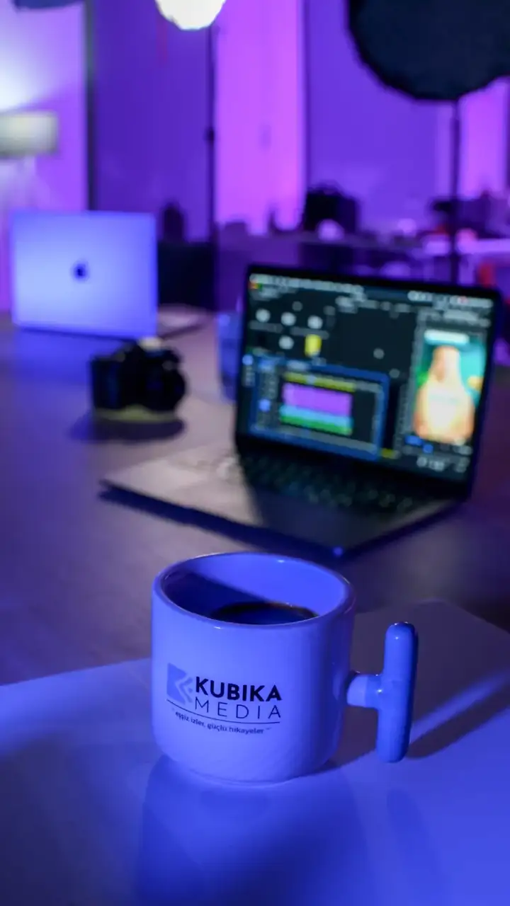Kubika Media stüdyosunda mor ışık altında kurgu masası ve logolu kupa
